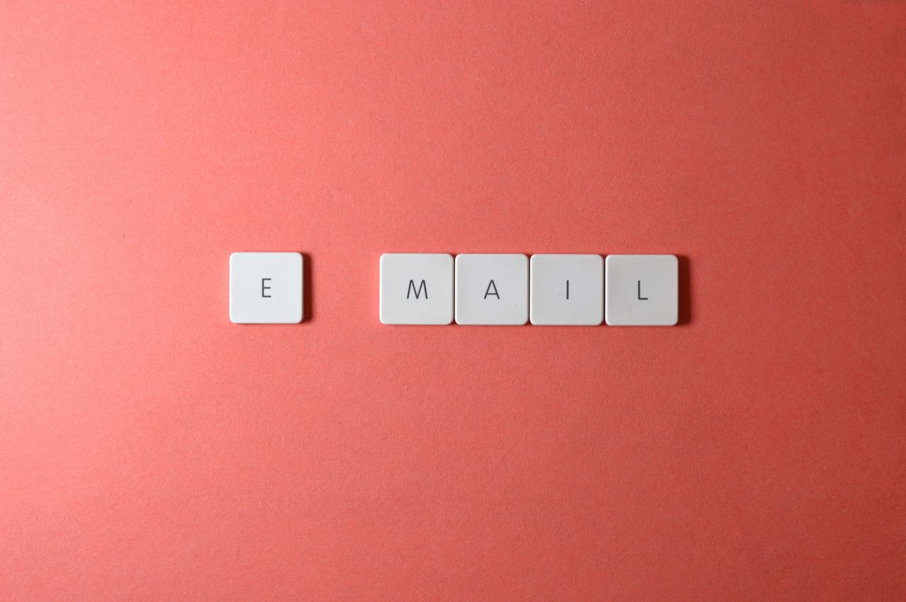 services-02 Vue en flat lay de tuiles de clavier formant le mot email sur un fond corail.